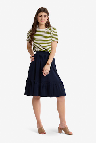 Woman wearing a striped green top with a navy blue knee length skirt