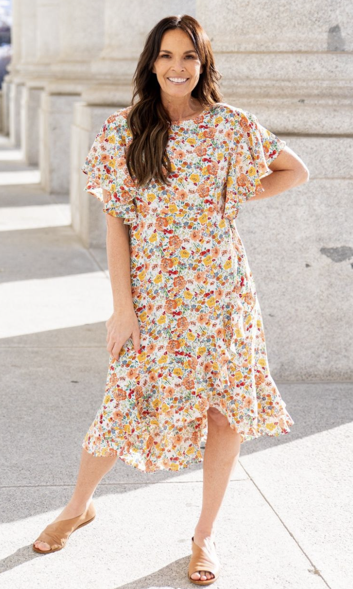 Smiling woman wearing a floral knee length dress and sandals