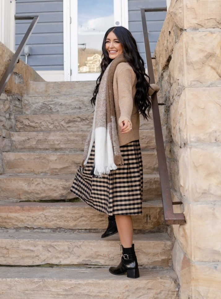 Woman walking up stairs wearing a midi skirt, sweater and scarf