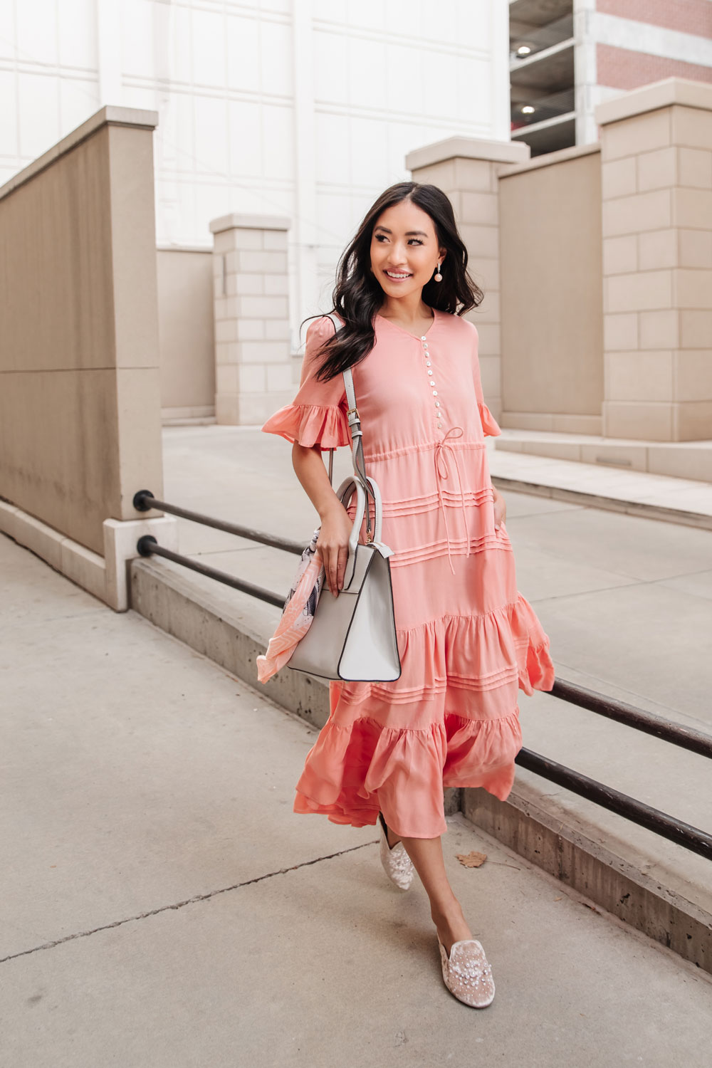 Women in pink tiered dress with gray purse